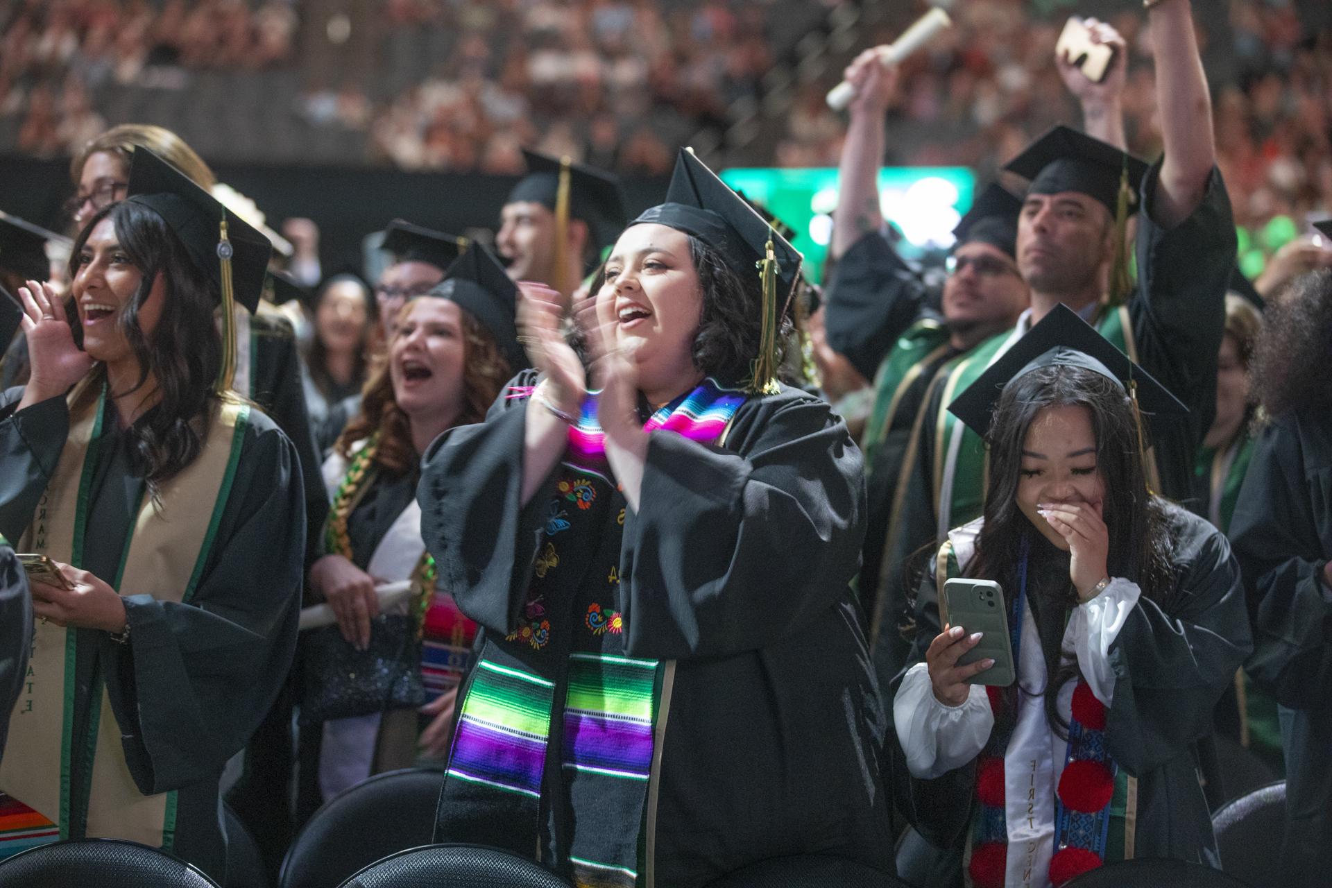 Gradutes in academic regalia celebrating during Commencement.